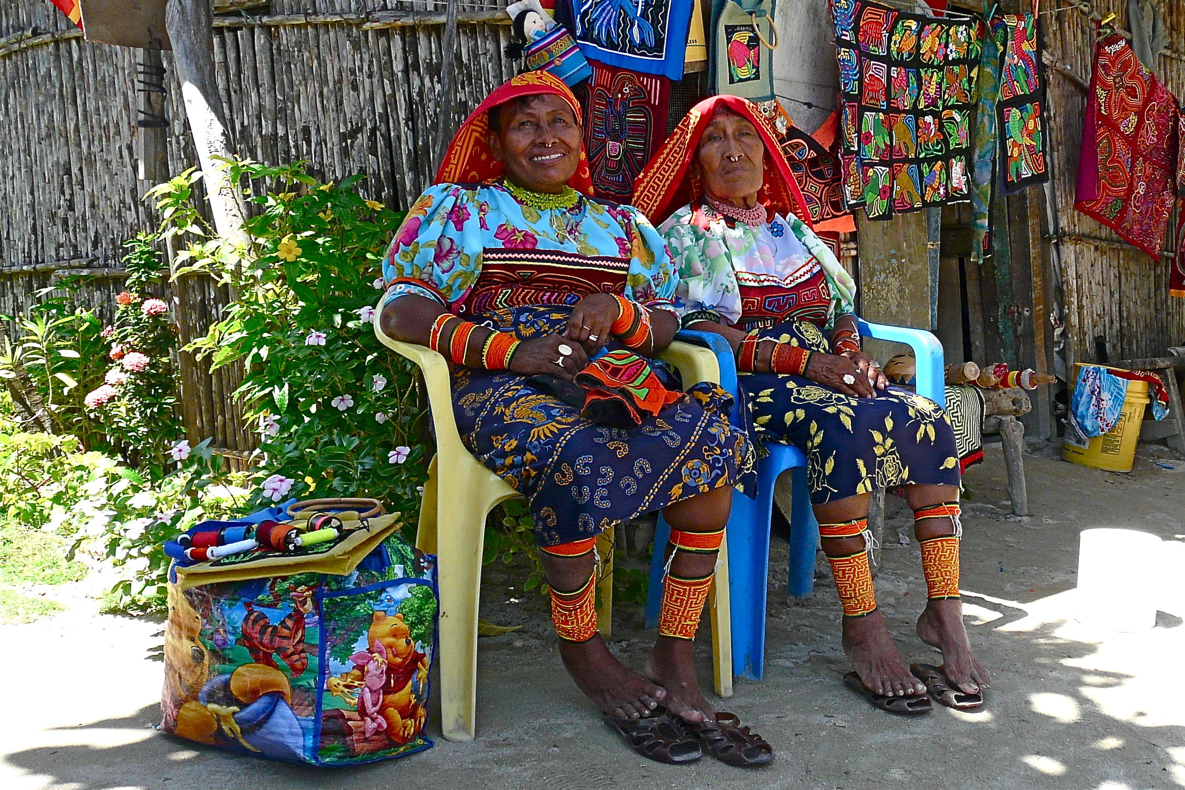 Two women sewing colorful blankets.