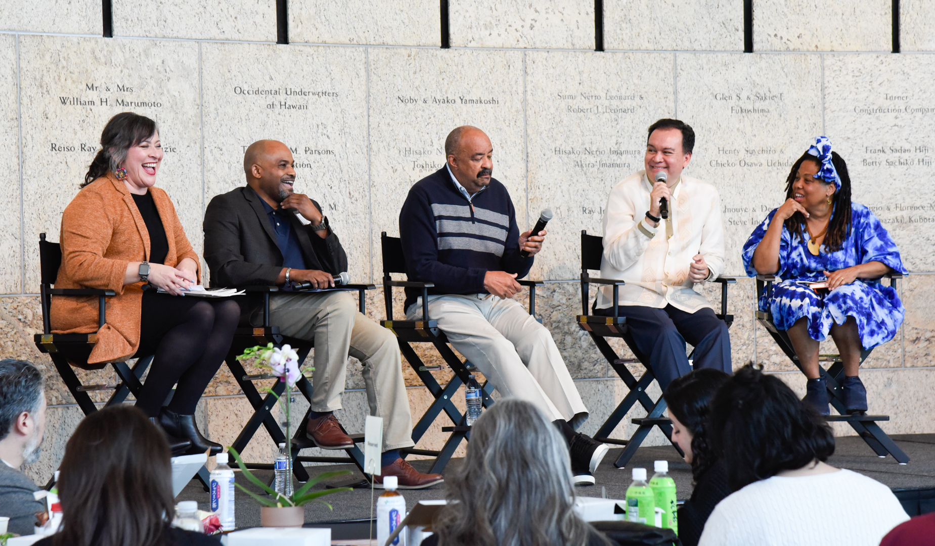 Five panelists on stage with microphones.