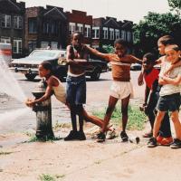 young children playing around a fire hydrant on a city street