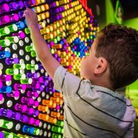 back of child, playing with wall of bright lights]