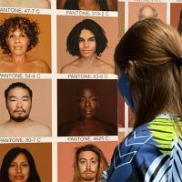 woman looking at exhibition panel with people with different skin tones labeled with pantone colors