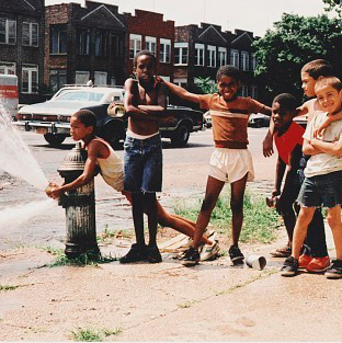A group of friends playing by a fire hydrant.