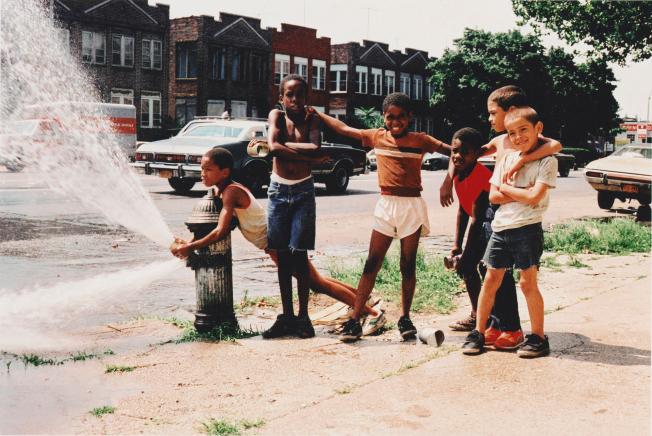 young children playing around a fire hydrant on a city street