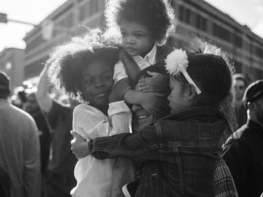 two daughters and a son hugging their smiling father 